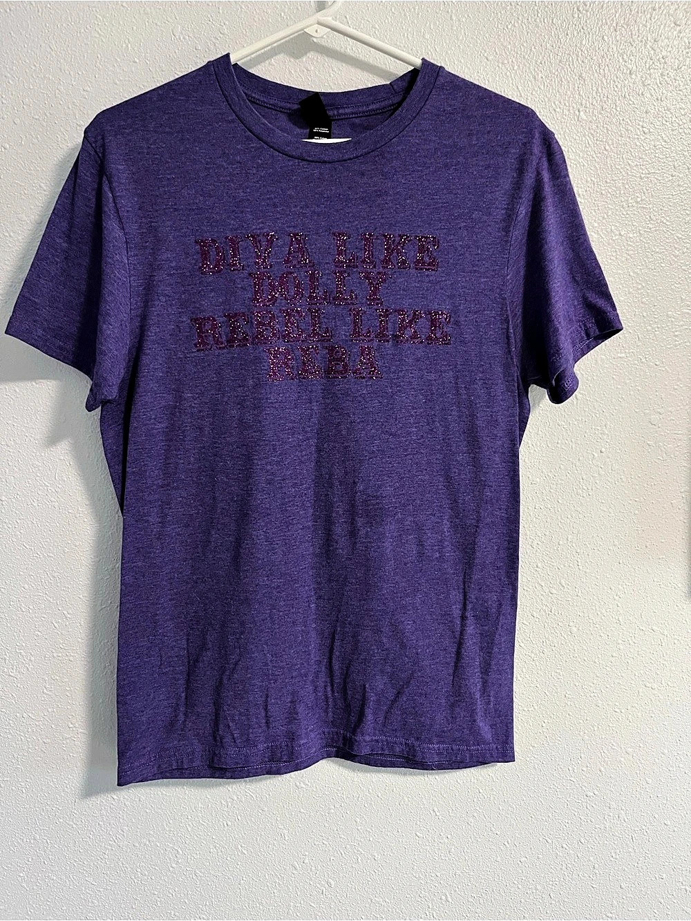 Short sleeve tee with glitter text reading “DIVA LIKE DOLLY REBEL LIKE REBA” Siz
